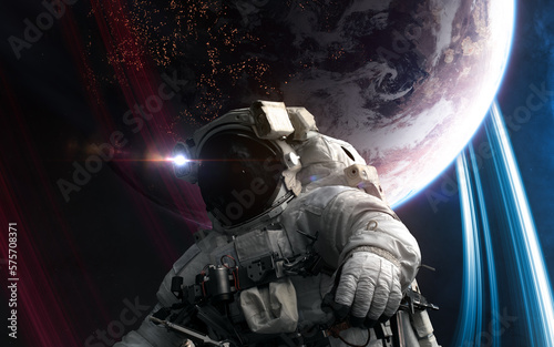 Astronaut in outer space in front of distant inhabited planet. Science fiction. Elements of this image furnished by NASA