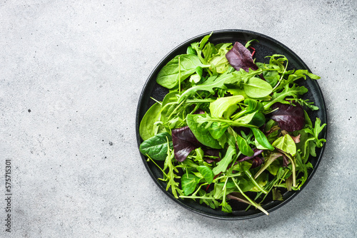 Green salad with fresh leaves in black plate. Healthy food, clean eating, diet. Top view.