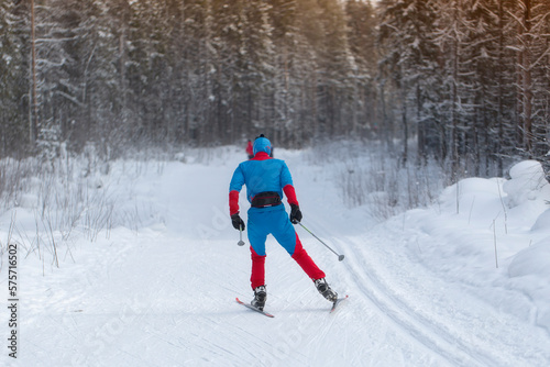 A man goes cross-country skiing in winter through the forest on a special track.