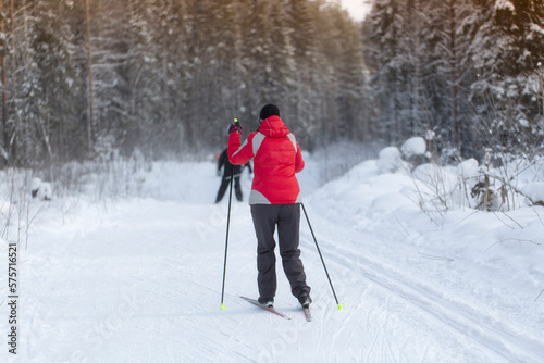 A man goes cross-country skiing in winter through the forest on a special track.