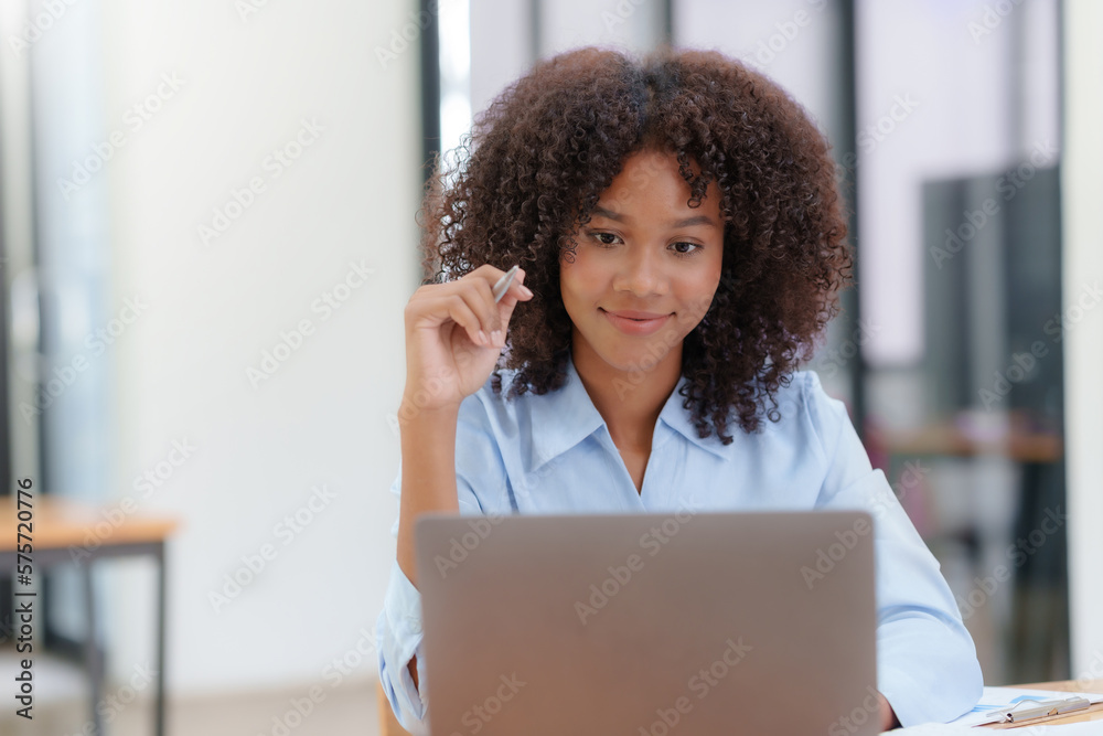 Happy businesswoman sitting and working with laptop computer in office.