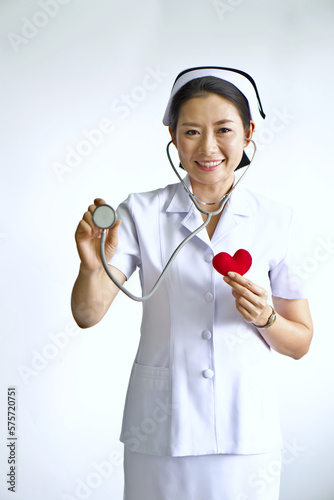 Selective focus on blur stethoscope and red heart in hand of the nurse. Beautiful Asian nurse smile, Medical treatment concept