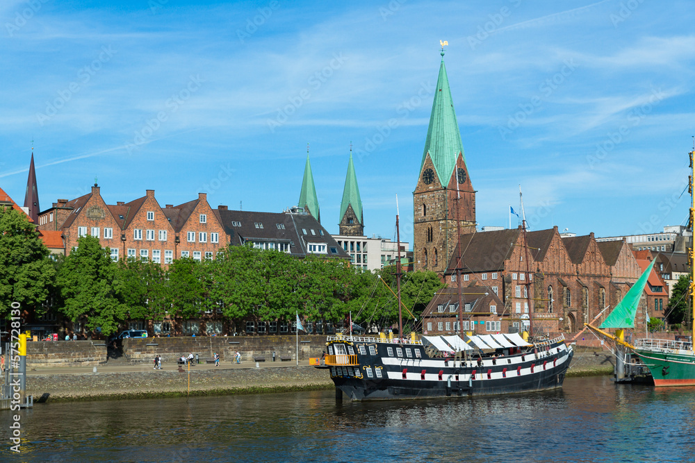 Naklejka premium Cityscape of Bremen with old architecture, historical wooden sailing ships and barge floating along the river Weser. Bremen, Germany, July 15, 2021