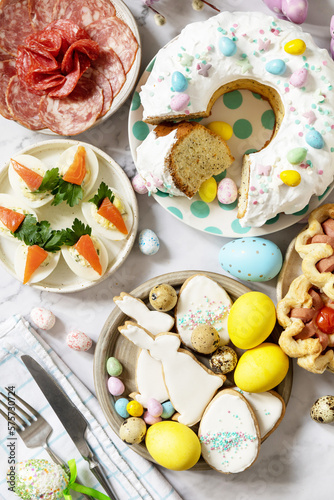 Festive dinner, Easter brunch. Easter table scene with an assortment of baking, desserts, stuffed eggs and dyed eggs on a marble background. View from above.