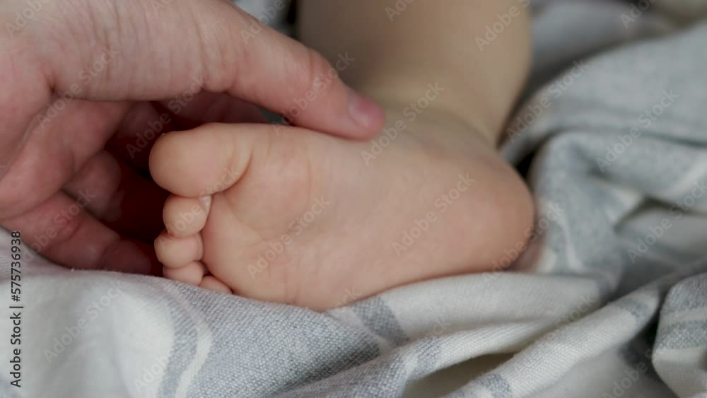 baby boy close up barefoot leg feet.infant toddler holding with small hands own feet.relaxing boy under blanket.mother woman hand massaging sole maternity concept love care baby boy close up barefoot leg feet.infant toddler holding with small hands own feet.relaxing boy under blanket.mother woman hand massaging sole maternity concept love care