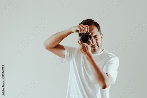 Male photographer taking a picture on a light background. Concept of technology, professions, lifestyles and arts.