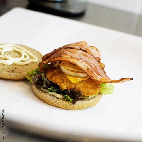 Burger with chicken and bacon on the kitchen table in the restaurant