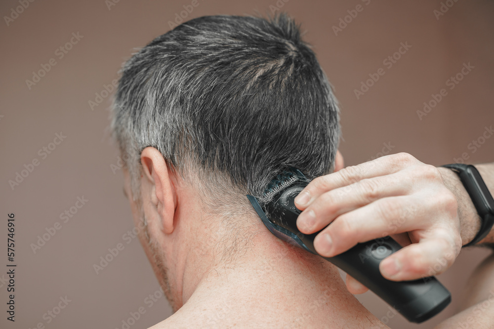 Man cutting his own hair with a clipper Man cutting his own hair with a clipper
