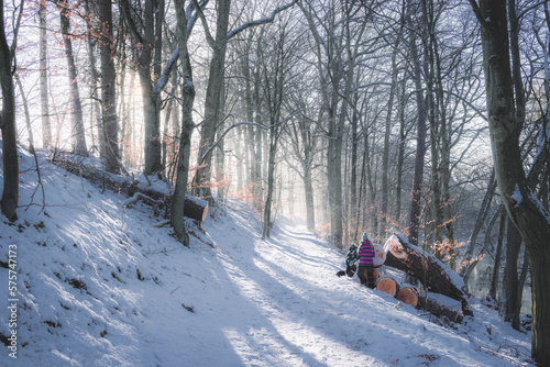 Snow-covered forest path where children play.