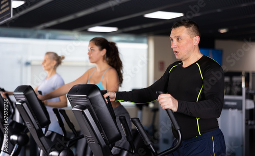 Middle-aged man in the gym is engaged in sports using an ellipsoid simulator. Healthy lifestyle and sport concept