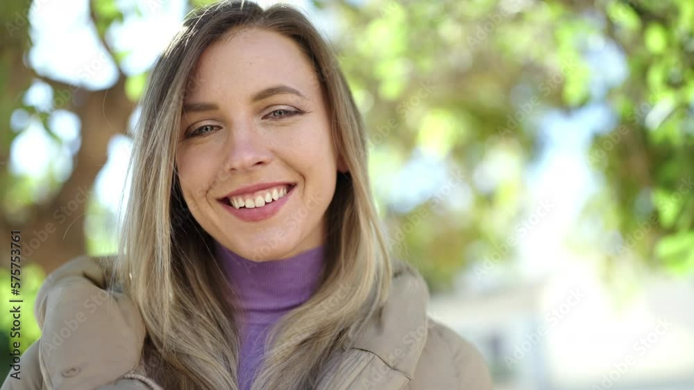 Young blonde woman smiling confident standing at park