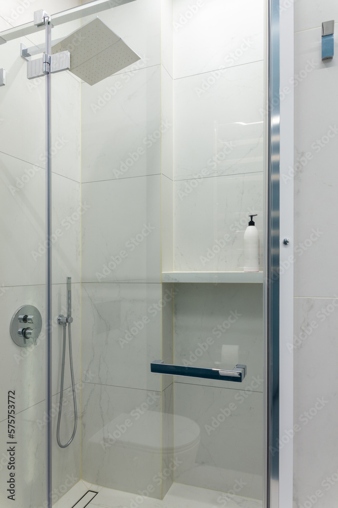 Close up modern glass shower in the white ceramic bath room. Close up modern glass shower in the white ceramic bath room.