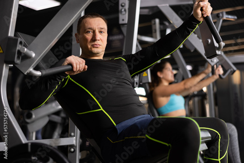 Athletic man is engaged in the simulator - develops biceps and triceps photo