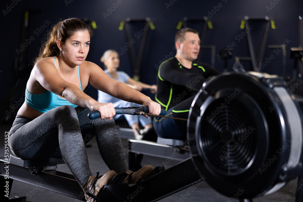Active young woman training at cable row machine in gym