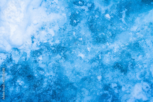 Close up photo texture of highlighted blue toned frozen water surface.