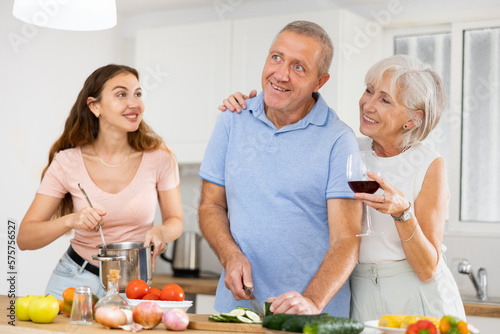 Portrait of smiling mature man, woman and daughter preparing family dinner at kitchen table