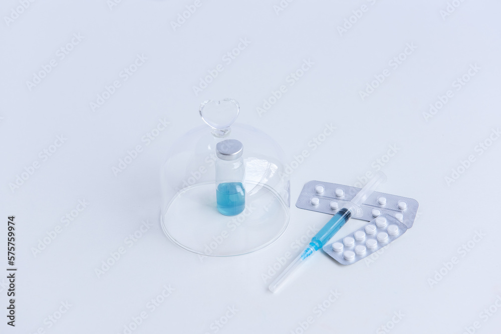 On white isolated background lie a syringe with medicine, a vial with a blue vaccine against viruses, pills for flu, colds. Medical preparations for the fight against the epidemic. Mock up, copy space On white isolated background lie a syringe with medicine, a vial with a blue vaccine against viruses, pills for flu, colds. Medical preparations for the fight against the epidemic. Mock up, copy space