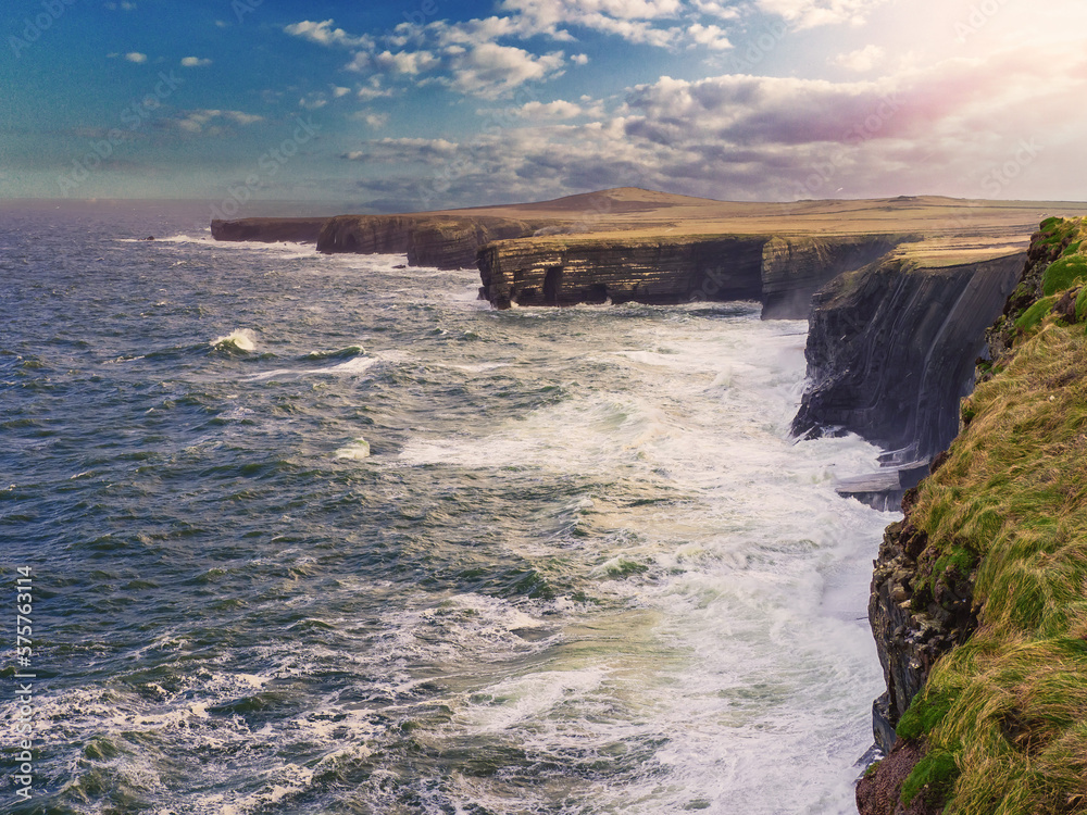 Obraz premium Beautiful scenery of Kilkee cliffs in county Clare, Ireland. Stunning Irish nature landscape. Day time, dramatic sky with clouds. Popular tourist and travel area with amazing view. Nature scene.