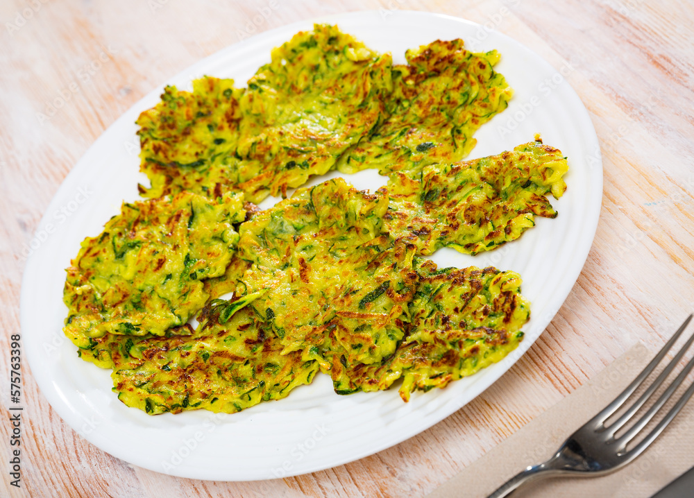 Zucchini pancakes with white sauce on withe plate. High quality photo