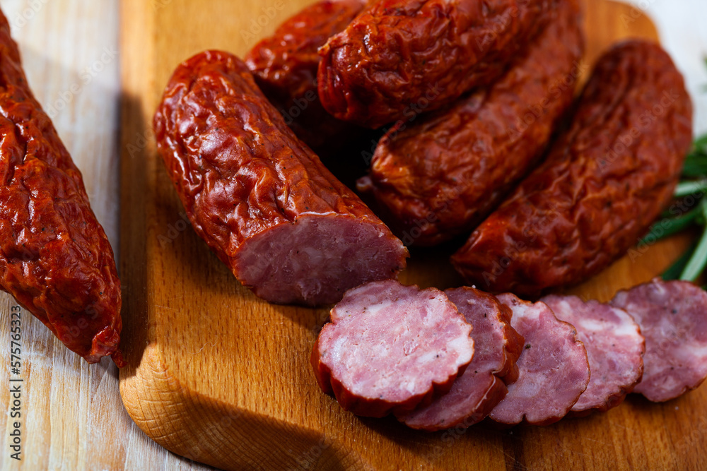 Tasty smoked ham sausages with spices on wooden background. Traditional Czech meat product