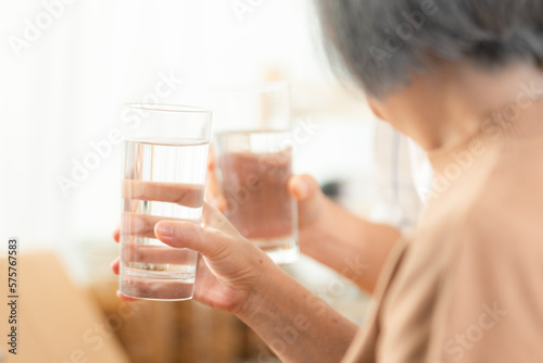 Family health care in house concept, Asian senior elderly couple drink a glass of water in kitchen room at home, Mature older thirsty grandparent holding clean mineral natural in glass, peace of mind
