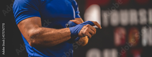 Closeup of hands of young male athlete trainer determined to workout for a healthy lifestyle tying band on hand for hand punch workout exercise in modern gym and fitness club
