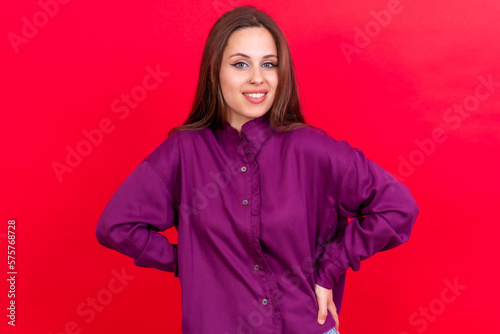 Close up portrait of a young caucasian woman in purple shirt isolated on red background, smiling © unai
