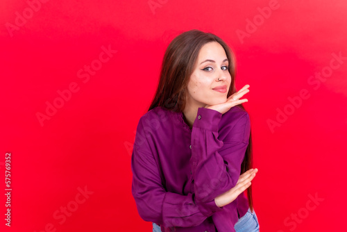 Close up portrait of young, cheerful isolated on red studio background in purple shirt smiling