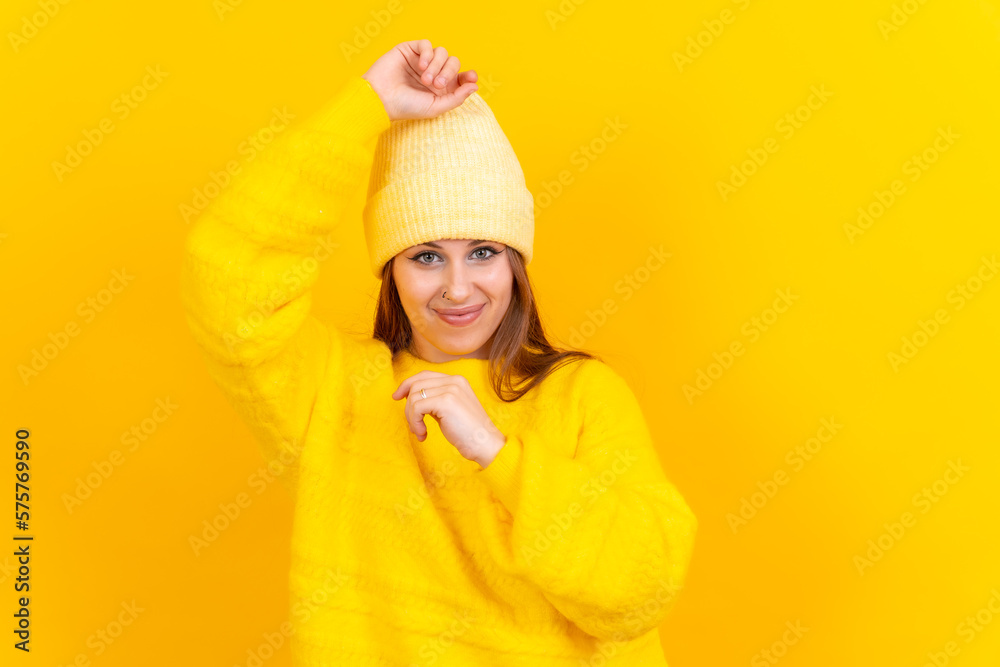 Photo portrait of a young woman dancing very happy isolated on a yellow background, wool sweater Photo portrait of a young woman dancing very happy isolated on a yellow background, wool sweater