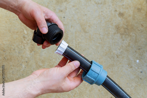 A plumber repairs a water supply system. Installation and quick disconnect connection of polyethylene water pipes for water supply.