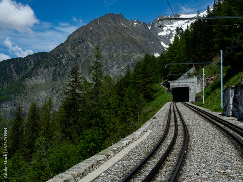 Scenic railway track winding through the French Alps near Chamonix. A breathtaking journey surrounded by lush forests, rugged peaks, and snow-capped mountains