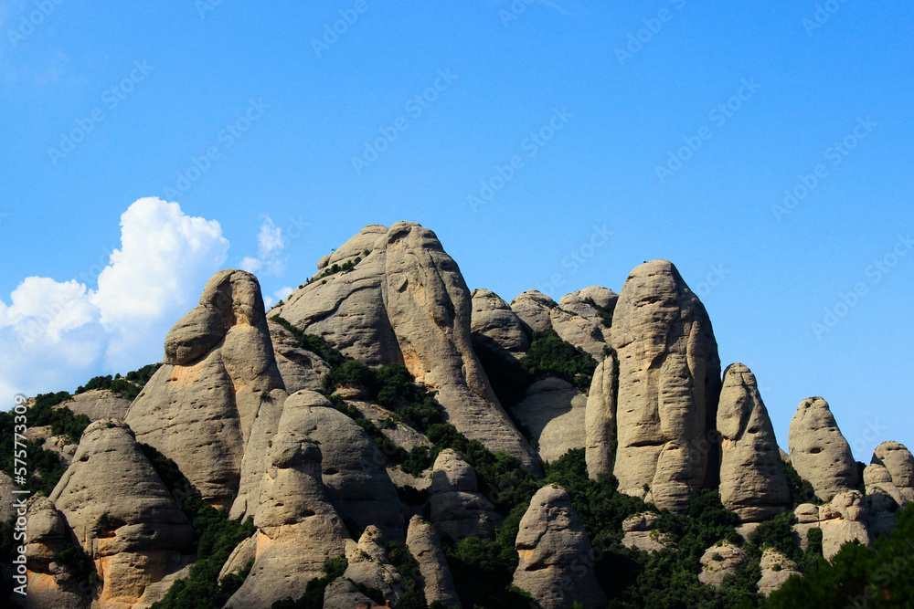a peak mountain of finger-like rock formations seen against the blue sky with few white clouds in the corner