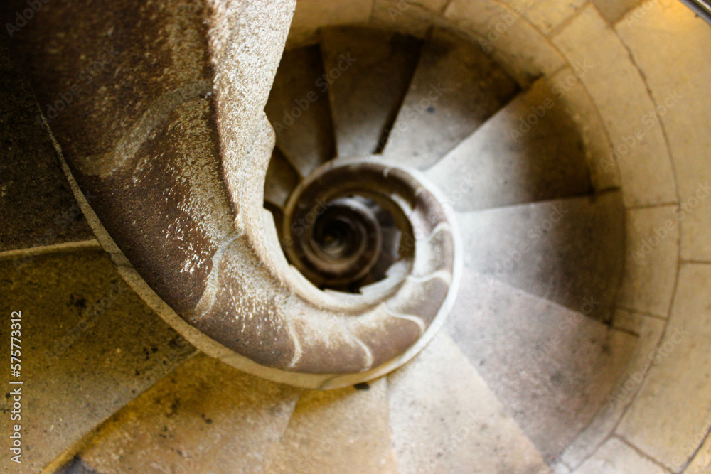 spiral staircase in light stone seen from above giving the impression of a tunnel towards infinity. spiral staircase in light stone seen from above giving the impression of a tunnel towards infinity.