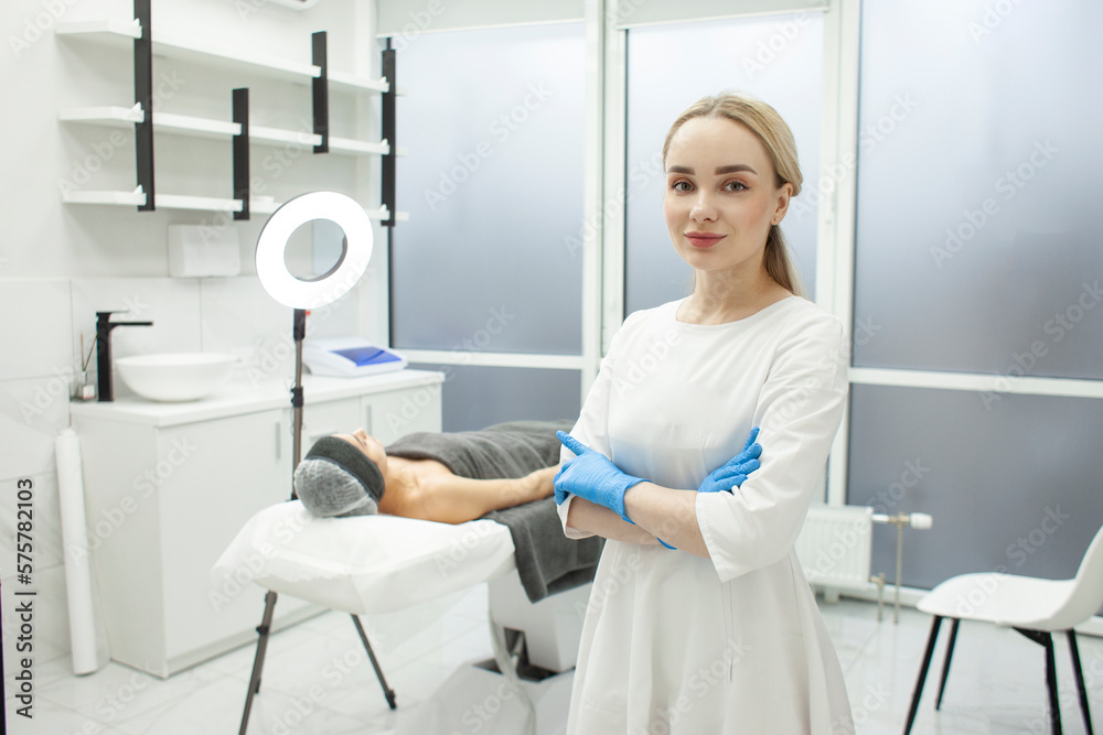 portrait of cosmetologist girl in cosmetology clinic, young dermatologist doctor in uniform stands with folded arms portrait of cosmetologist girl in cosmetology clinic, young dermatologist doctor in uniform stands with folded arms