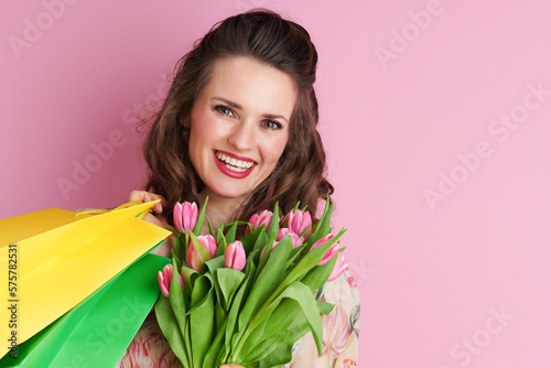 Portrait of smiling stylish woman in floral dress on pink