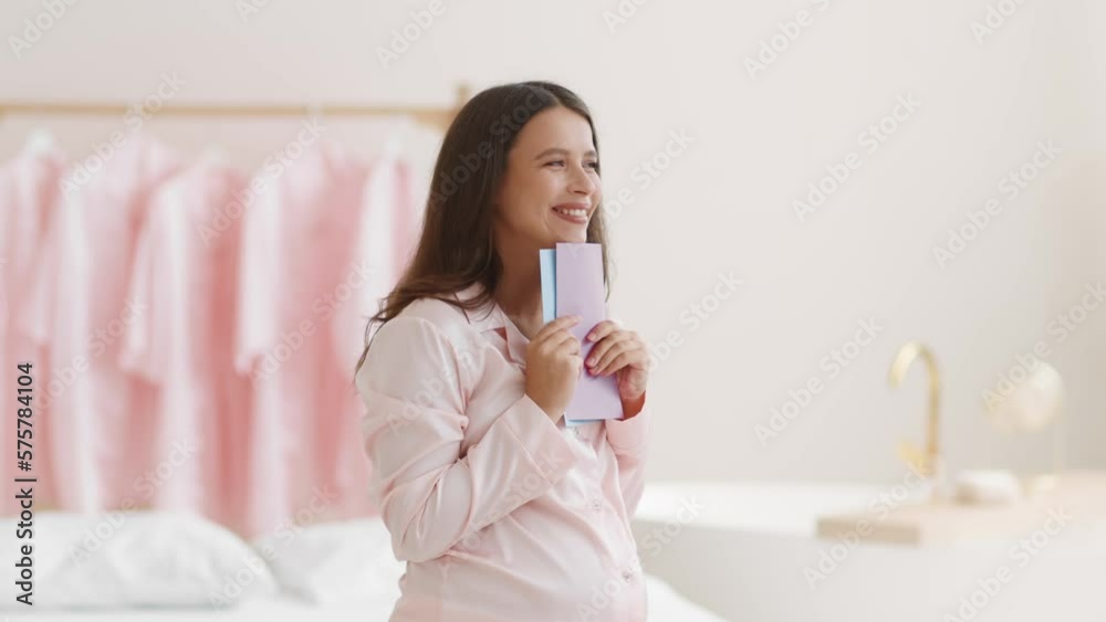 Young pregnant woman holding blue and pink cards, guessing whether it's boy or girl, dreaming at home, free space Young pregnant woman holding blue and pink cards, guessing whether it's boy or girl, dreaming at home, free space