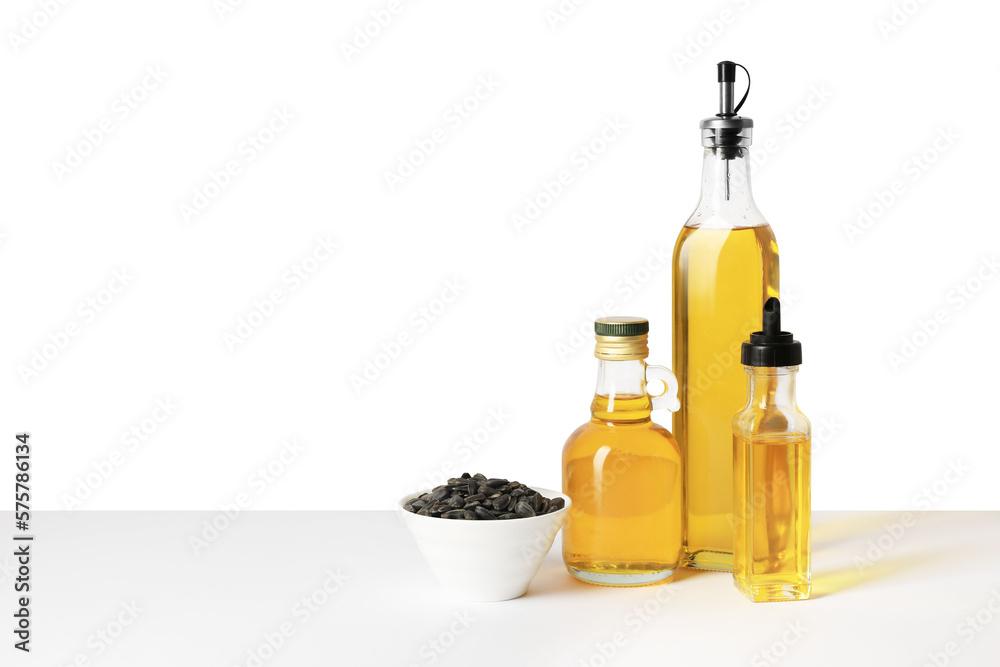 Bottles of different cooking oils and sunflower seeds on white background, space for text Bottles of different cooking oils and sunflower seeds on white background, space for text