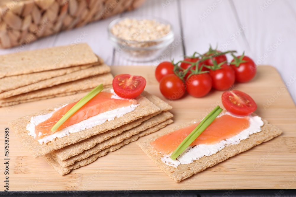 Tasty crispbreads with salmon, cream cheese, green onion and tomato on white wooden table, closeup Tasty crispbreads with salmon, cream cheese, green onion and tomato on white wooden table, closeup