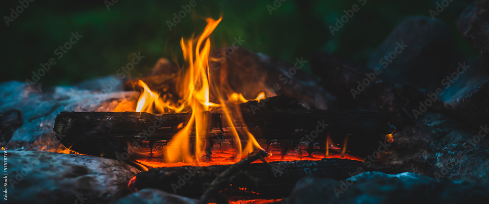 Vivid smoldered firewoods burned in fire close-up. Atmospheric warm background with orange flame of campfire. Unimaginable full frame image of bonfire. Burning logs in beautiful fire. Wonderful flame.