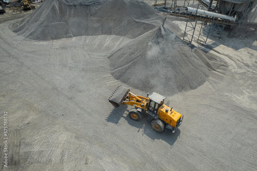 Sand loaders are shoveling rocks into dump trucks. Sand loaders are shoveling rocks into dump trucks.