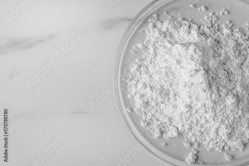 Petri dishes with calcium carbonate powder on white marble table, closeup. Space for text