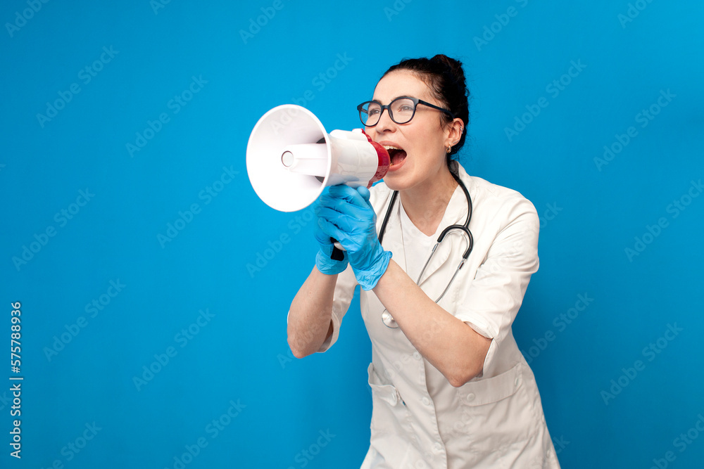 doctor girl in uniform shouting into loudspeaker on blue background, female nurse in medical gown announces doctor girl in uniform shouting into loudspeaker on blue background, female nurse in medical gown announces