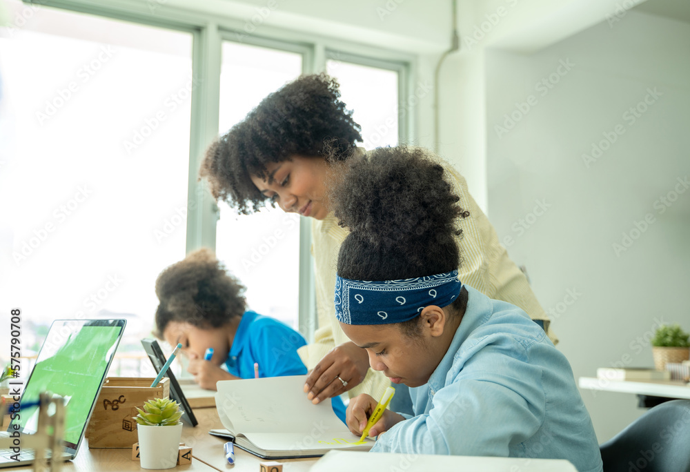 Young African American children sitting at school desk attentively listening to his teacher,Student doing test in primary school.