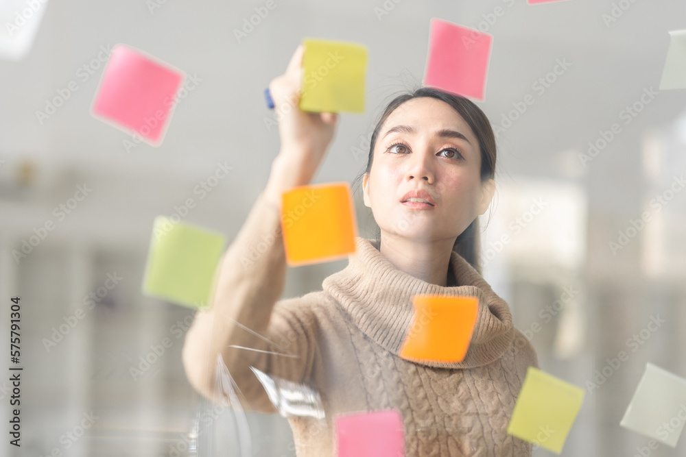 Business Asian woman meeting at office and use post it notes in glass wall to share idea. Brainstorming business office concept. Sticky note on glass wall. Business Asian woman meeting at office and use post it notes in glass wall to share idea. Brainstorming business office concept. Sticky note on glass wall.