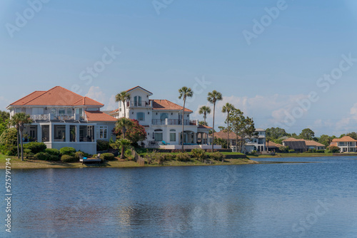 Rich neighborhood with mansions near Four Prong Lake in Destin  Florida. Mansions villas at the shore of the lake with plants and trees on its yards against the blue sky background.