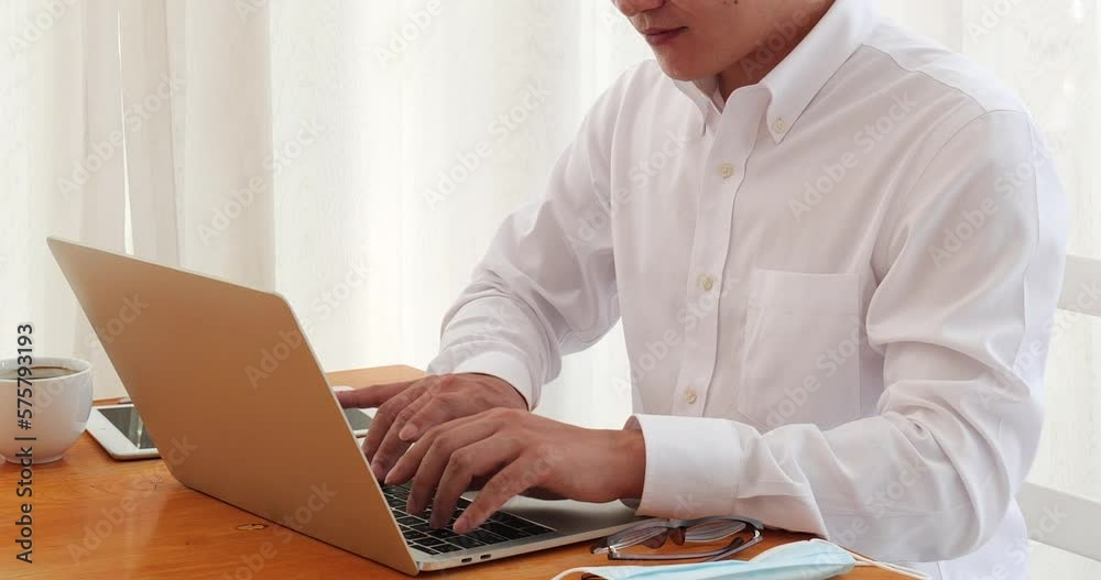 Asian man freelance using laptop at home office desk. man reading financial graph chart Planning analyzing computer data. Asian male people working office business stuff, coffee cup at home office Asian man freelance using laptop at home office desk. man reading financial graph chart Planning analyzing computer data. Asian male people working office business stuff, coffee cup at home office