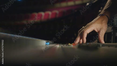 sound engineer fingers on audio mixing console fader in recording, broadcasting studio