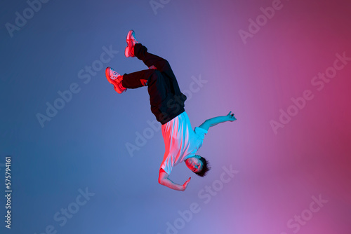 Canvastavla young guy falls upside down in the air, man levitates and flies down in neon lig