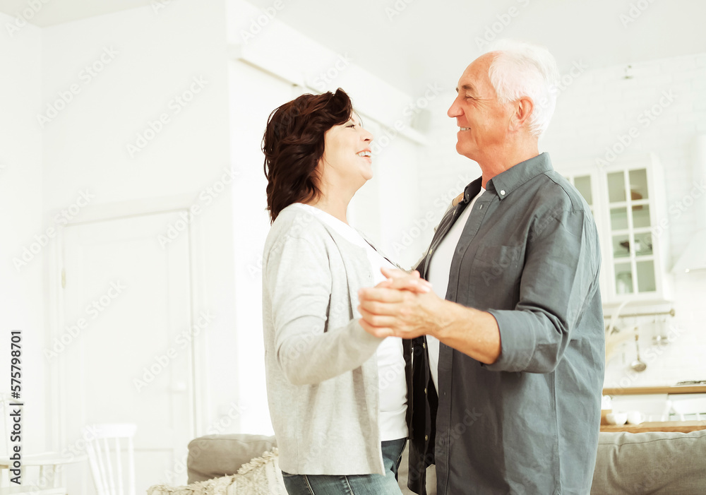 Obraz premium Happy active elderly senior couple dancing in kitchen. Lifestyle and old people concept.