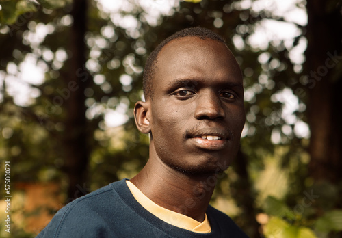 A young black man is walking in the park.